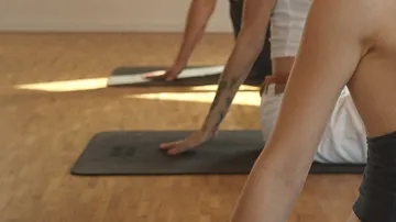 Yoga practitioners stretch out on mats in a sunny room.