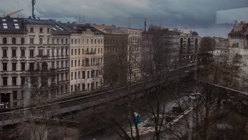 Urban buildings along a street under cloudy skies.