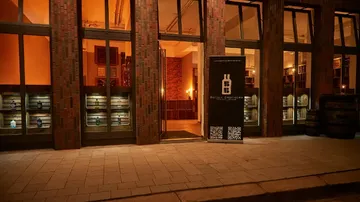 Eingang zu einer Bar, beleuchtet, mit Fass-Details.