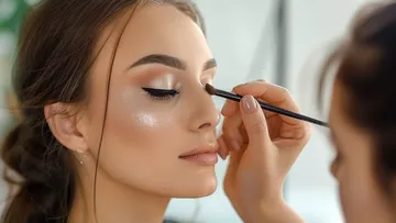 Frau erhält Augen-Make-up-Anwendung in heller Umgebung.