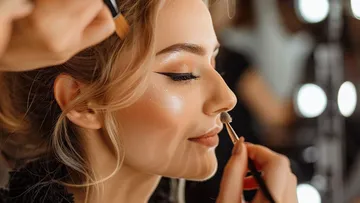 Frau erhält Make-up, beleuchtet von Friseursalon-Spiegeln.