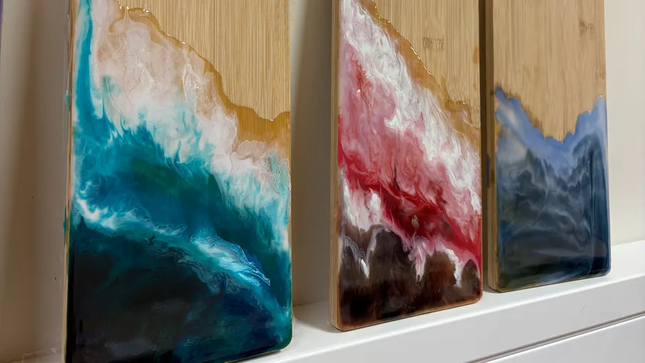 Three wooden boards with ocean-themed resin art.