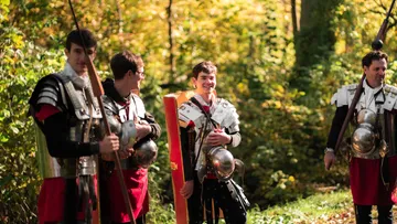 People in Roman soldier costumes in a forest.
