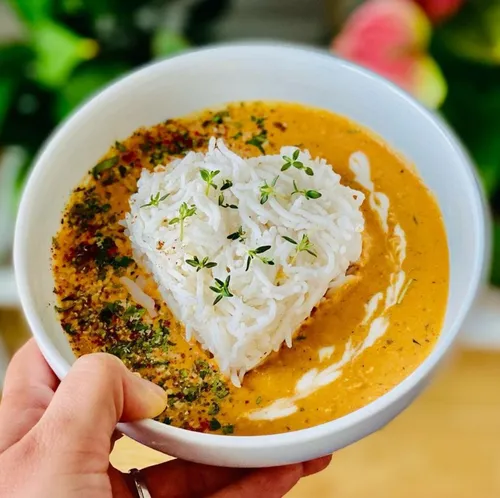 Herzförmiger Reis auf Curry in einer Schüssel, Hand haltend.