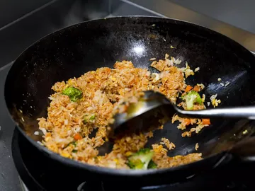 Fried rice is stirred in a pan.
