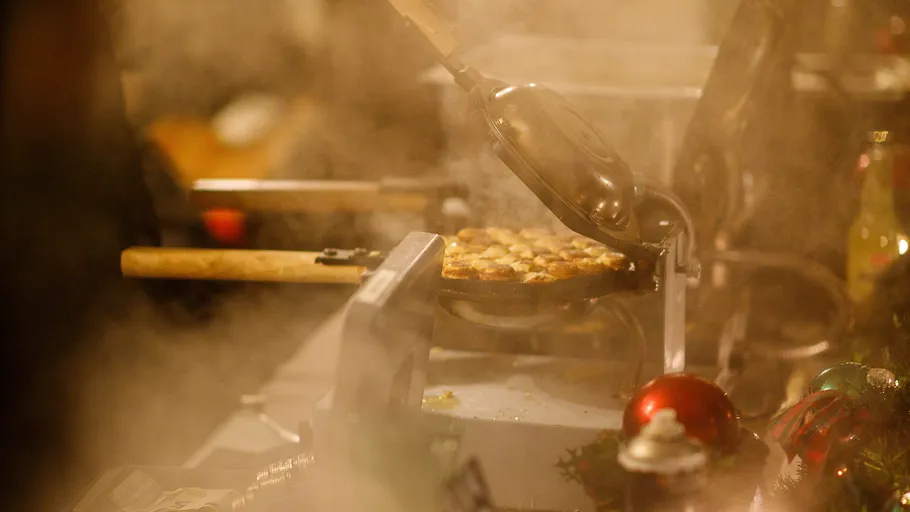 Person, die Waffeln in einer dampfenden Küche zubereitet.