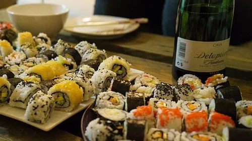 Verschiedene Sushi-Rollen auf Tellern mit Wein.