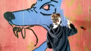 Person, die ein blaues Wolf-Wandgemälde an die Wand sprüht.