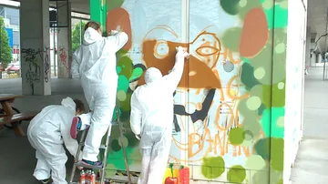 Leute, die Graffiti an eine Wand malen.