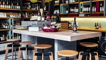Innenausstattung der Weinbar mit Holzhockern, Regalen, Flaschen.