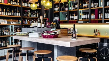 Wine shop with wooden table and stools.