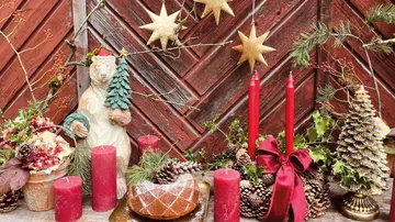 Christmas decorations with candles, bear statue, stars, and pine cones.