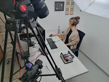 Eine Person sitzt am Schreibtisch, nutzt Computer.