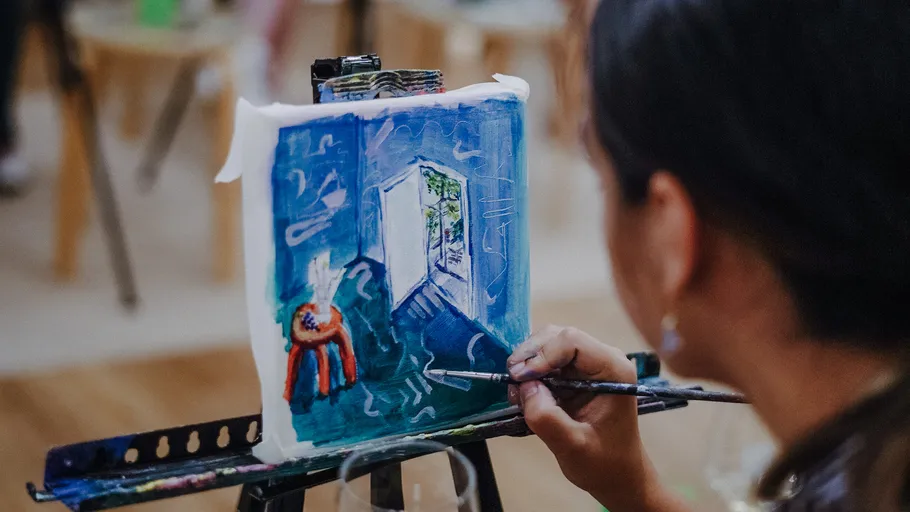 Person painting abstract indoor scene on canvas.