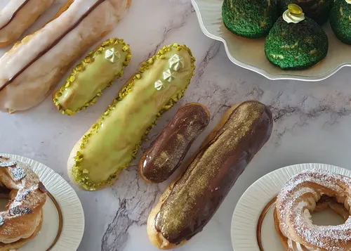 Verschiedene Eclairs und Gebäck auf Marmoroberfläche.