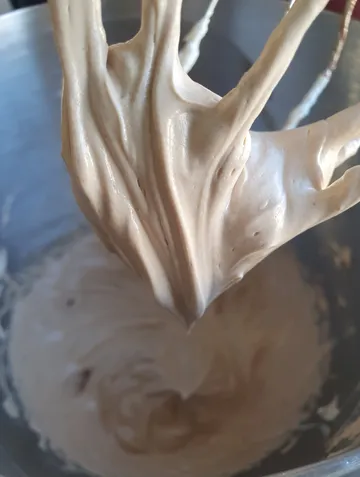 Whipped cream on a beater over mixing bowl.