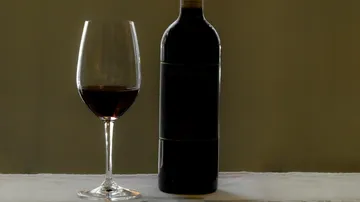 Wine glass and bottle on table.