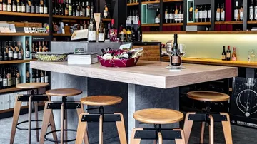 Moderne Weinbar mit Holzhockern und Flaschen.