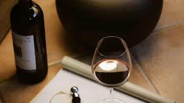 Weinflasche und Glas auf Fliesenboden.