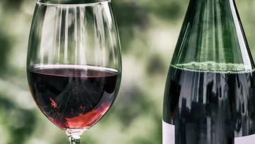 Weinglas und Flasche auf verschwommenem Hintergrund.