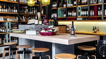 Modern wine bar with stools and shelves of bottles.