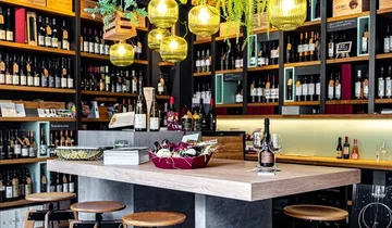 Moderne Weinbar mit Hockern und Flaschenregalen.