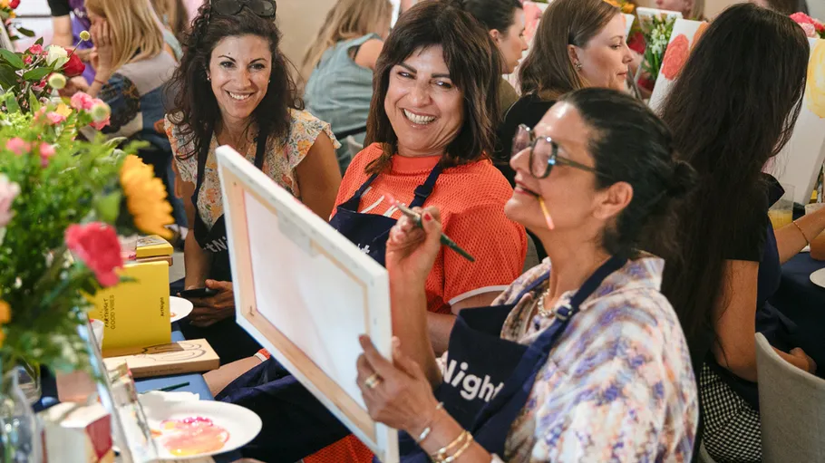 Frauen malen und lächeln auf einer Veranstaltung.