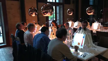 Group painting at indoor studio with dim lighting.