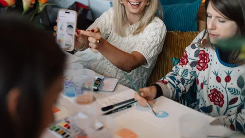 Leute, die drinnen an einem Tisch malen.