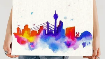 Colorful city skyline watercolor painting held by hands.