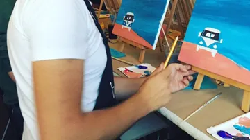 Person painting a van on easel indoors.