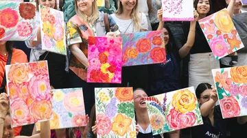 Gruppe, die im Freien farbenfrohe Blumenbilder hält.