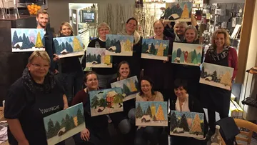 Group of people holding winter landscape paintings.