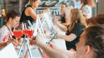 People painting and drinking wine indoors.
