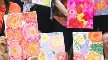 Gruppe, die farbenfrohe Blumenmalereien ausstellt.