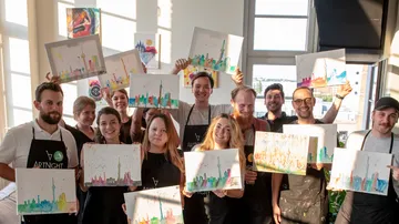 Group holding colorful paintings indoors.