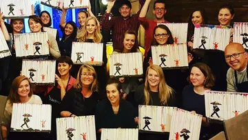 Group holding paintings of silhouette with umbrella.