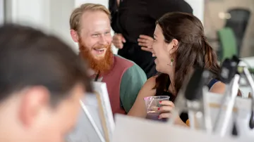 Zwei Menschen, die in einer sozialen Umgebung lachen.