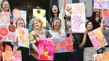 Gruppe von Frauen, die farbenfrohe Blumenbilder in der Hand halten.