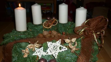 Advent wreath with four candles, one lit.