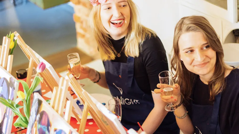 Two women enjoy a painting activity indoors.