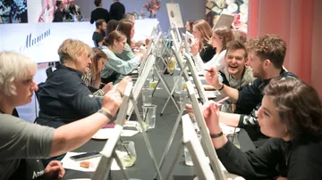 People painting at easels, enjoying an art class.