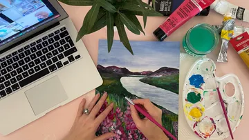 A person paints on a landscape painting with colors.