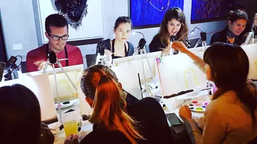 People painting on canvases in a workshop.