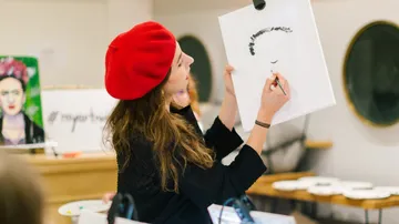 Woman in red beret paints a portrait indoors.