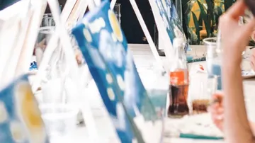 People painting on canvases at tables.
