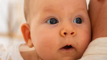 Baby looking curiously over shoulder.