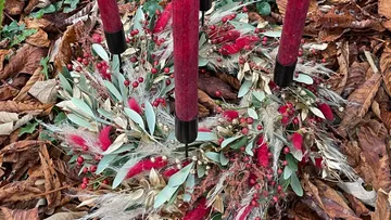 Wreath with red candles on fallen leaves.