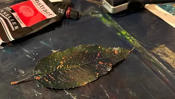 Blatt neben Acrylfarbe auf den Tisch gemalt.