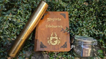 Buch, Rolle und Glas im Grünen.